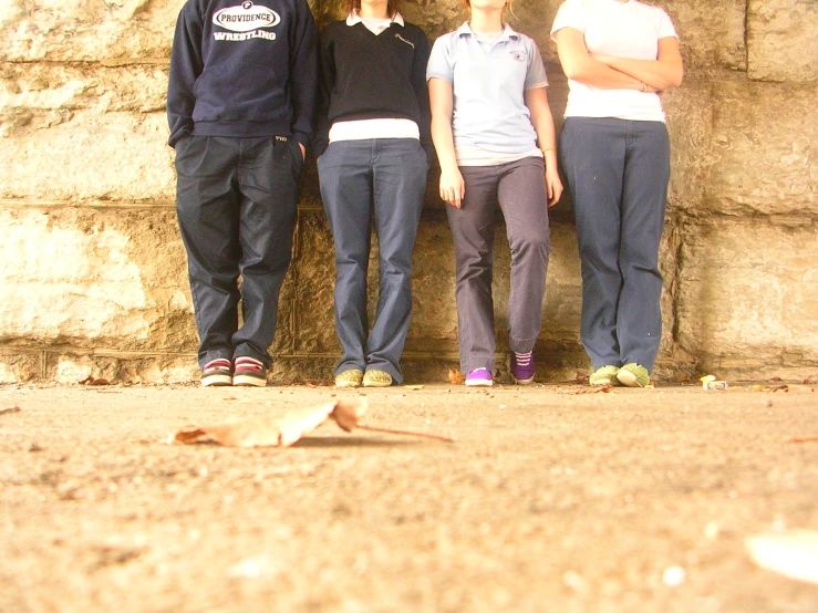 four people standing in front of a rock wall