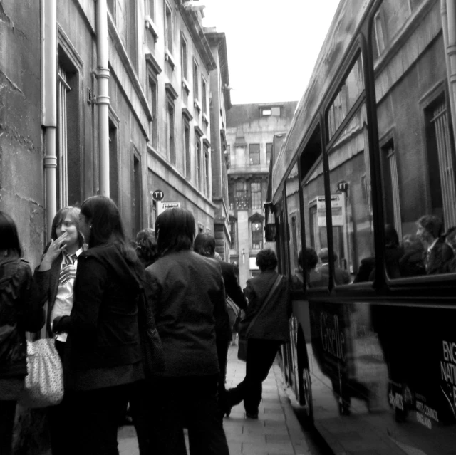 a group of people boarding a bus in front of some buildings