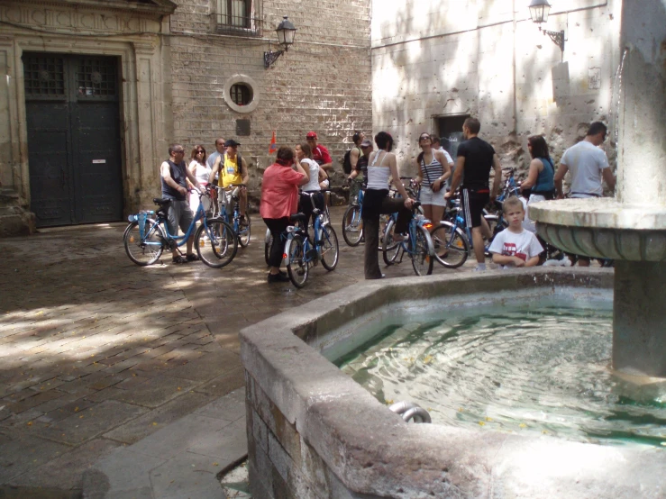 a fountain with water and many people riding bikes