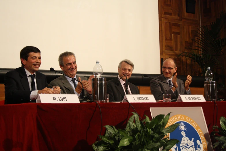 five men smile at the camera as they sit at a table