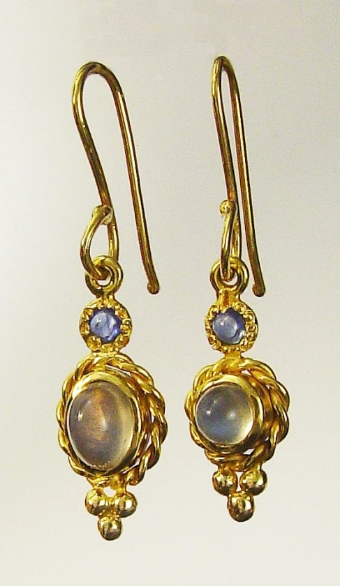 two gold earrings on a white table