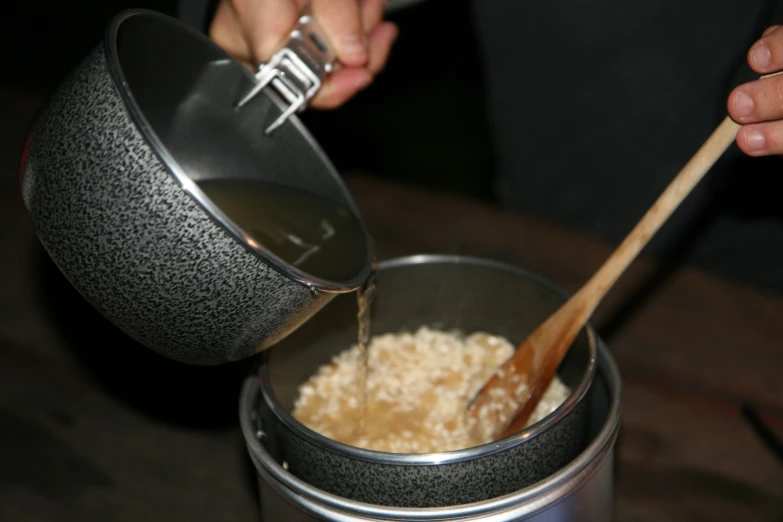 a person is stirring some food into a metal pan