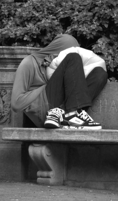 black and white po of a person wearing sneakers sitting on a bench