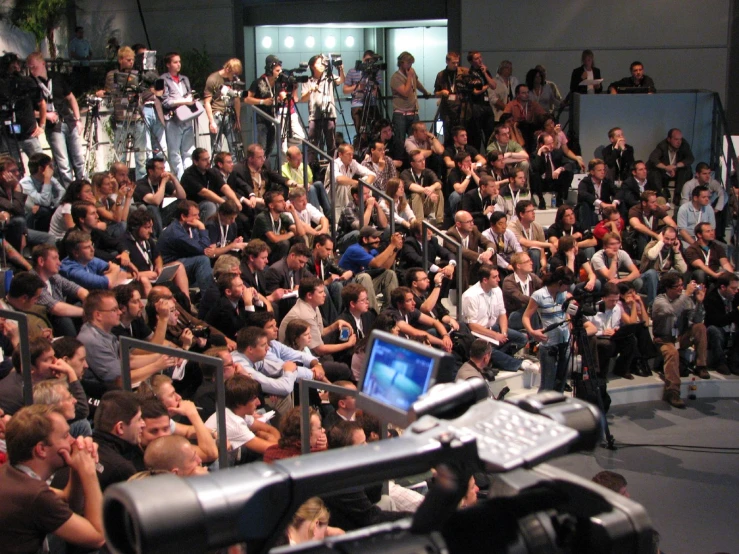 an outdoor event with a large group of people behind a laptop