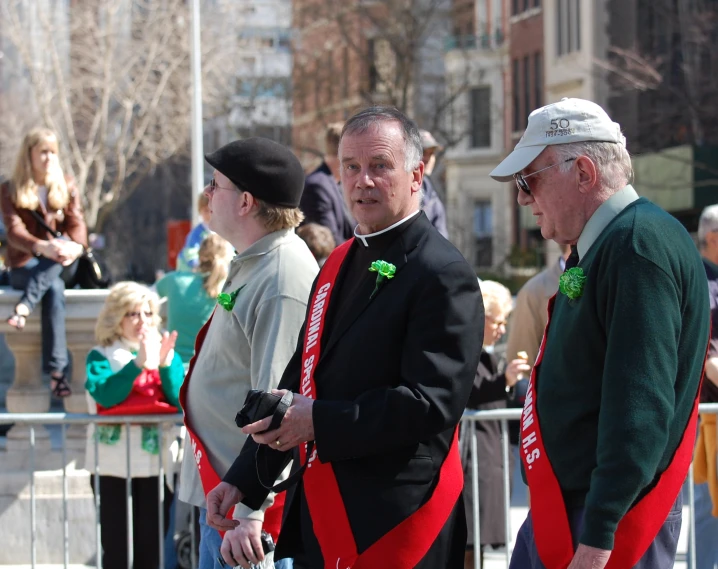 men in green and red outfits standing near a crowd of people