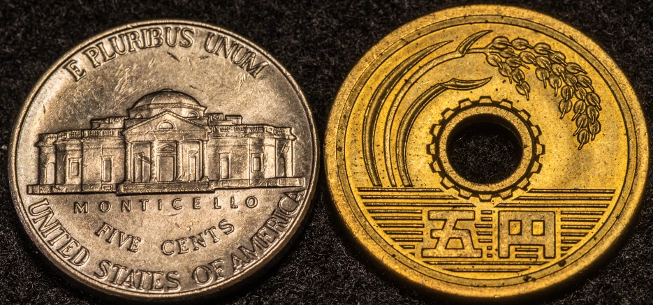 two old foreign currency pieces are pictured on a black surface