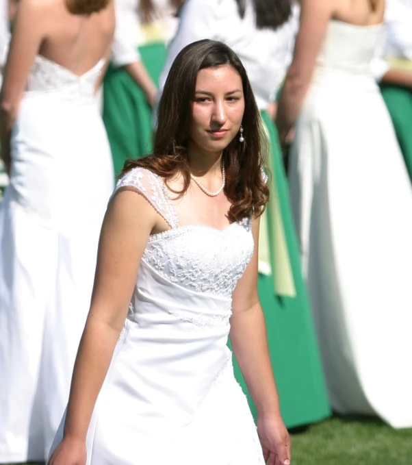 two women standing in a field one is wearing a wedding dress