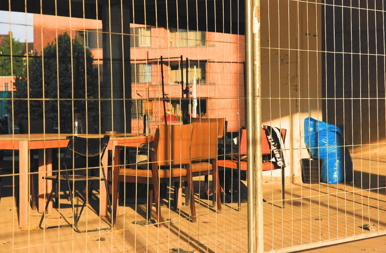 a table and chairs are behind a fence with a large mirror in the background