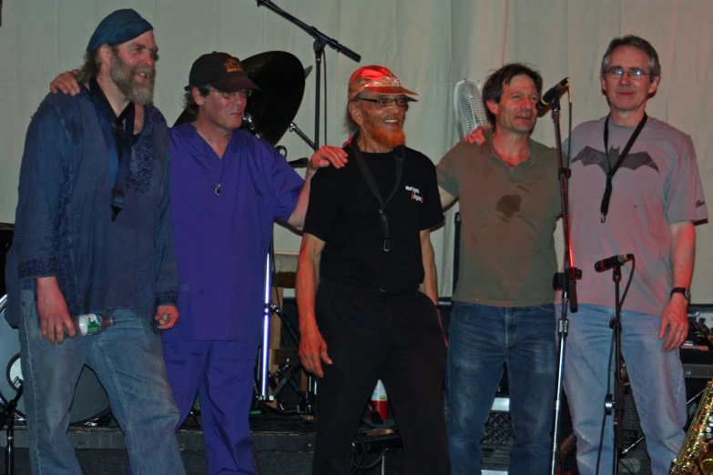 four men stand together with microphones at a concert