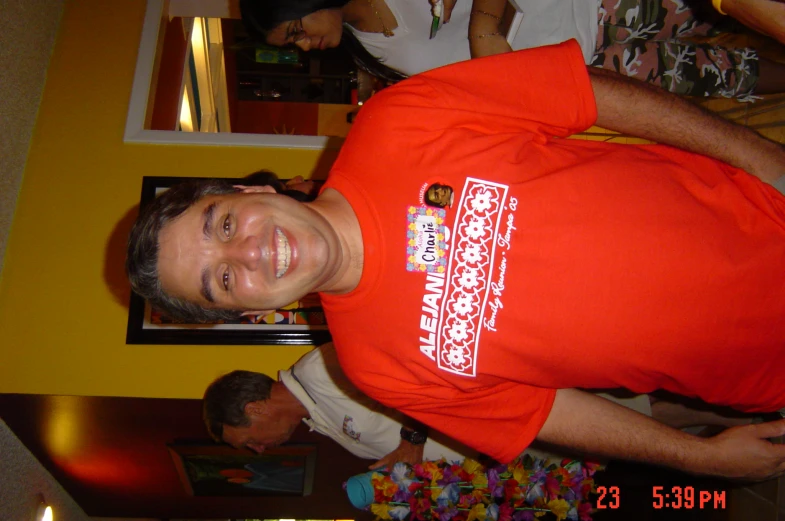 a man in an orange t - shirt standing in a room