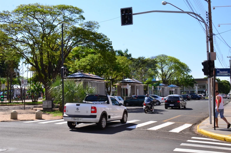 a city street with cars, trees and people on sidewalks