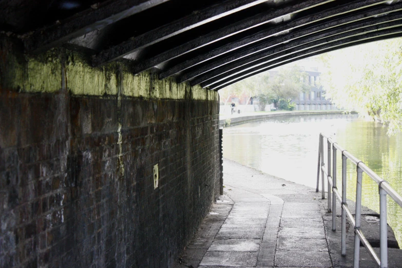 a brick wall is under a bridge over water