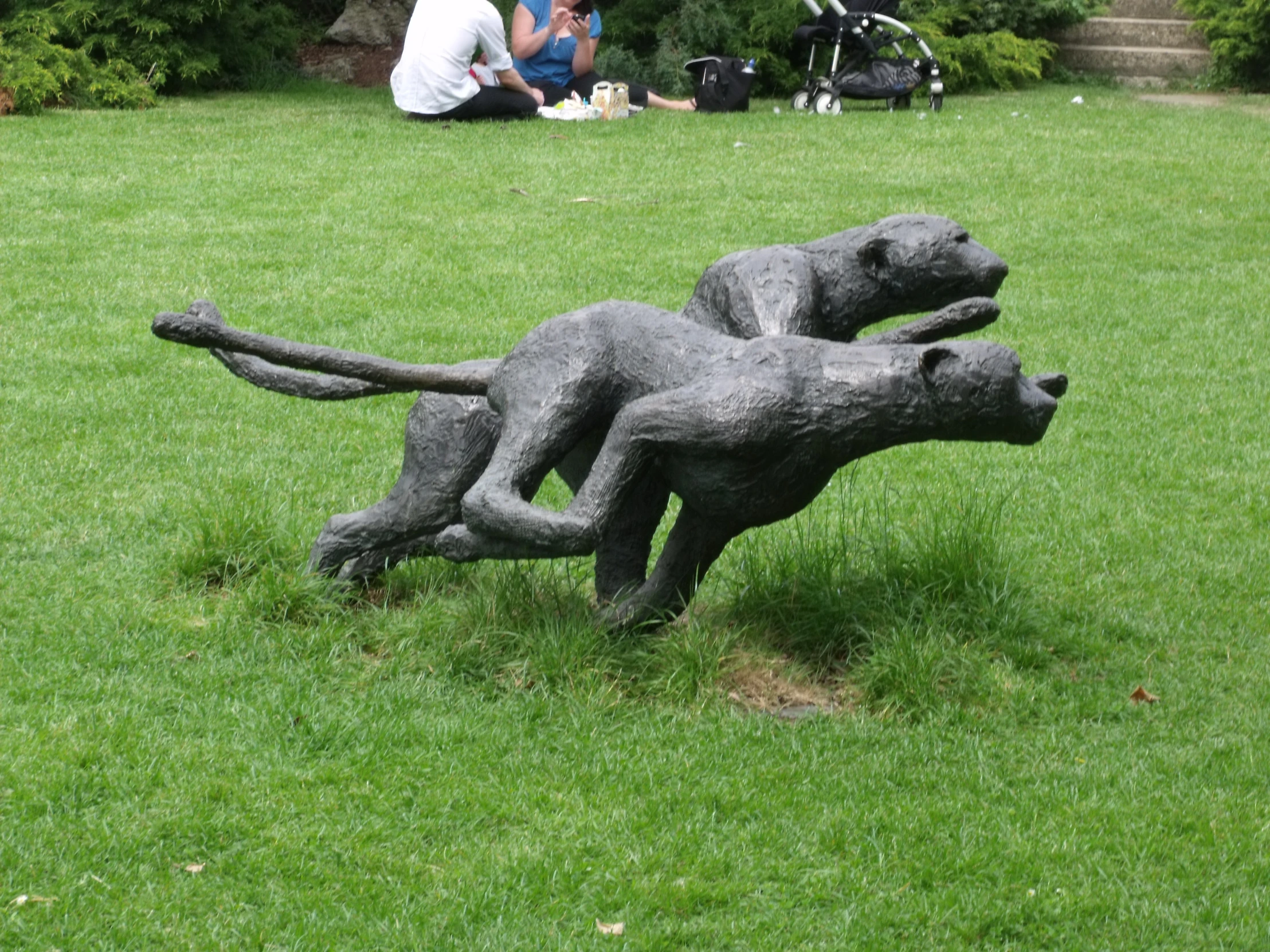a metal sculpture of two cats chasing each other