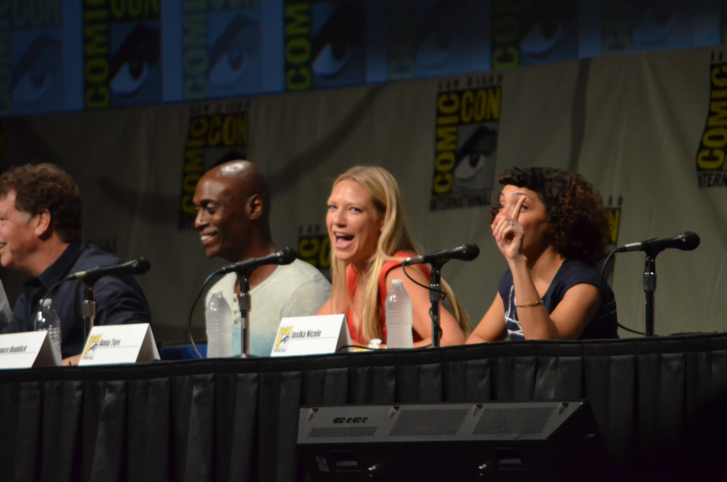 three actors are on stage at a panel