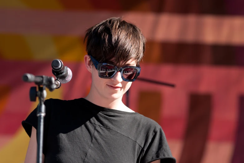 a woman with sunglasses and microphone on stage