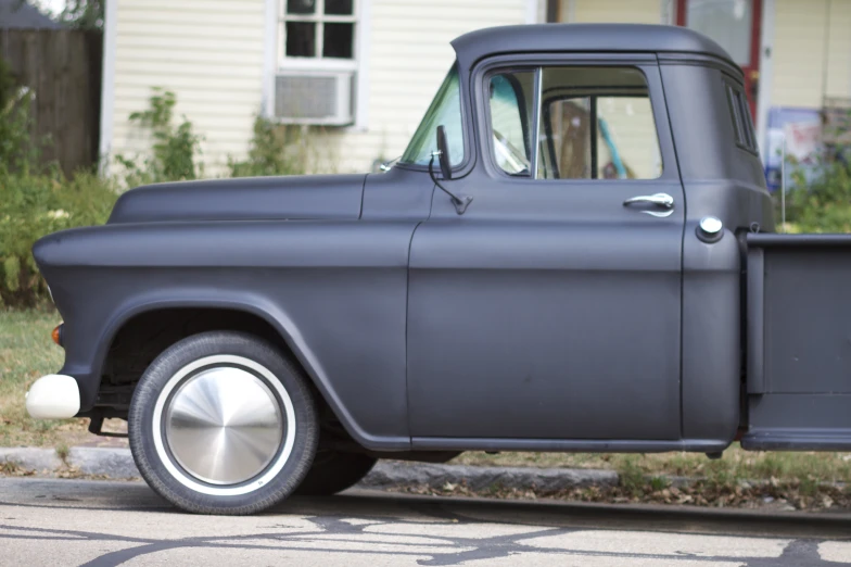 a gray classic pickup truck parked in front of a white house