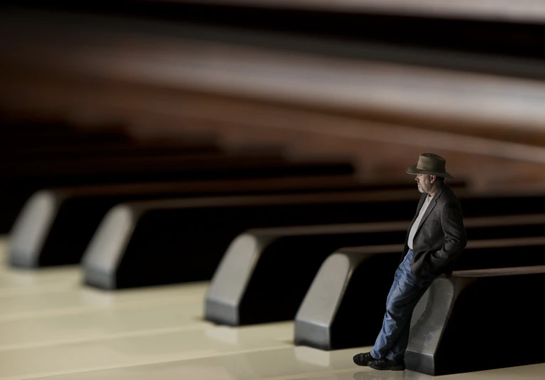 a man in a suit standing on a bench by some musical keyboards