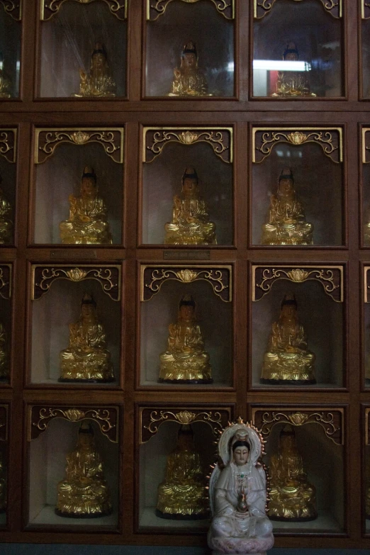 a statue surrounded by many gold buddha statues