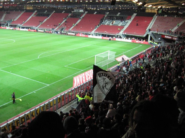 fans stand on the sidelines of a soccer field as a group of people watch