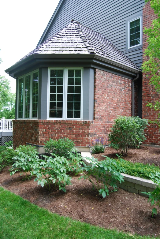 a brick house is well kept in a garden
