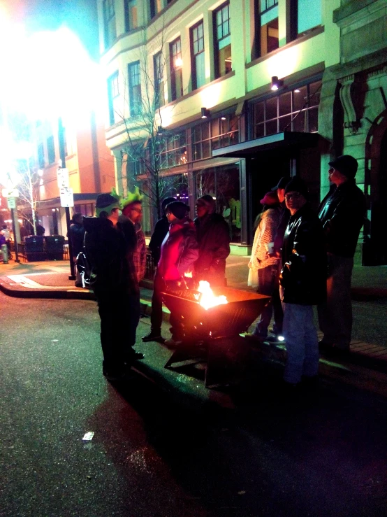 a group of people standing in the street by a police car