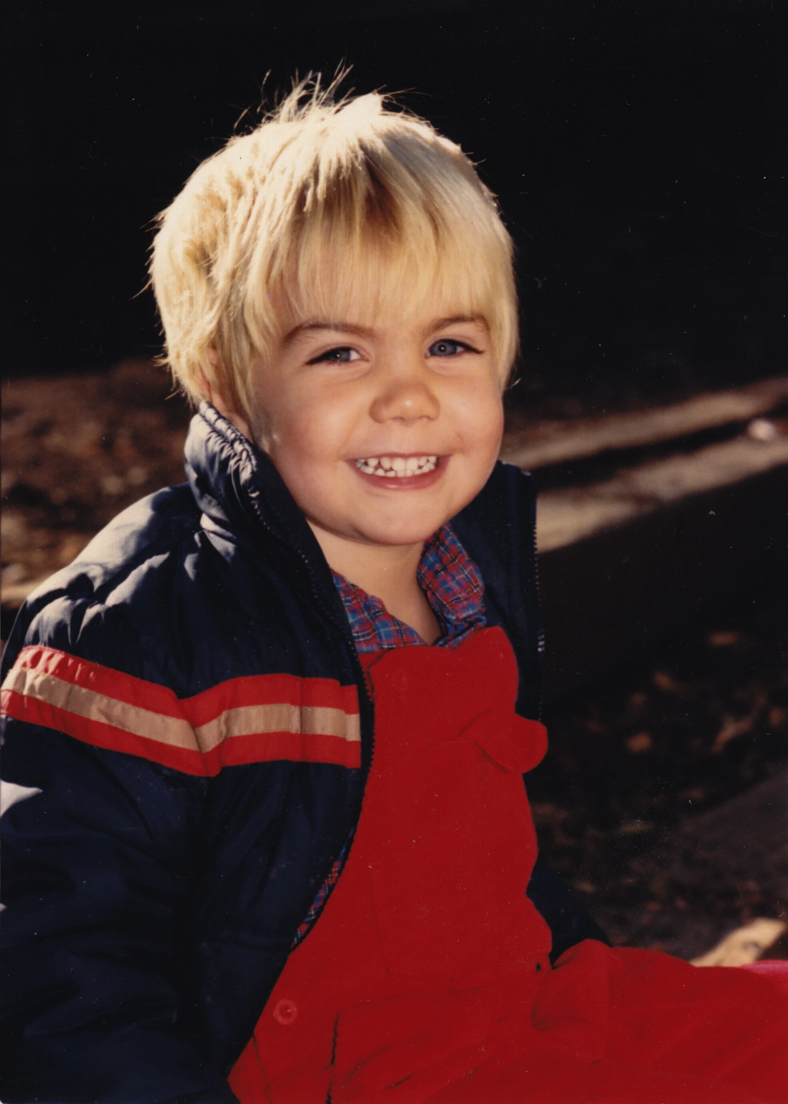 a boy wearing red and blue is smiling at the camera