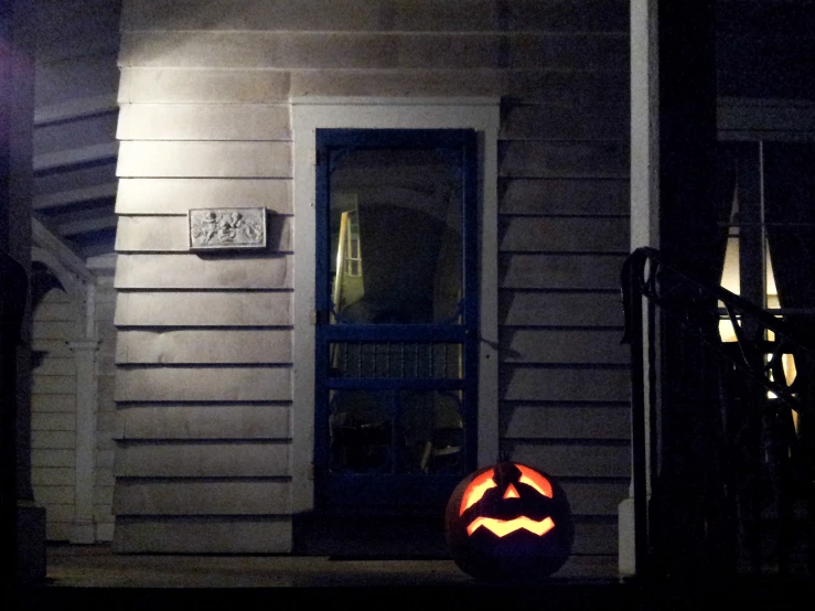 a halloween pumpkin on a front porch at night
