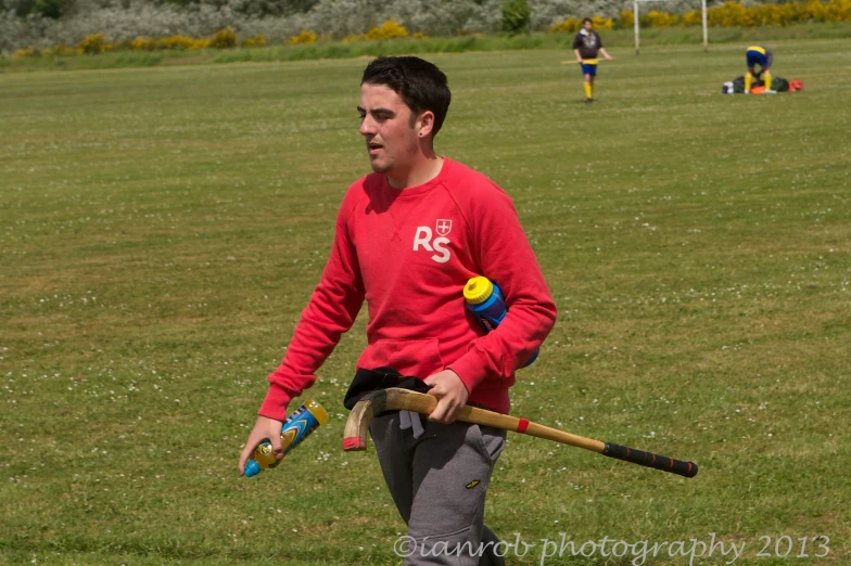 a man is throwing a baseball bat with balls and poles in the grass