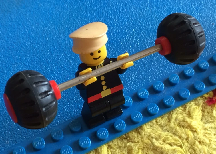 a lego man is lifting soing with a barbell