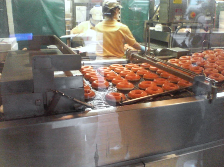 a woman is making donuts at the factory