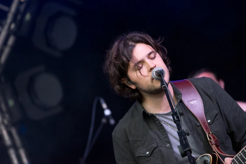 a man on a guitar playing an instrument with his eyes closed