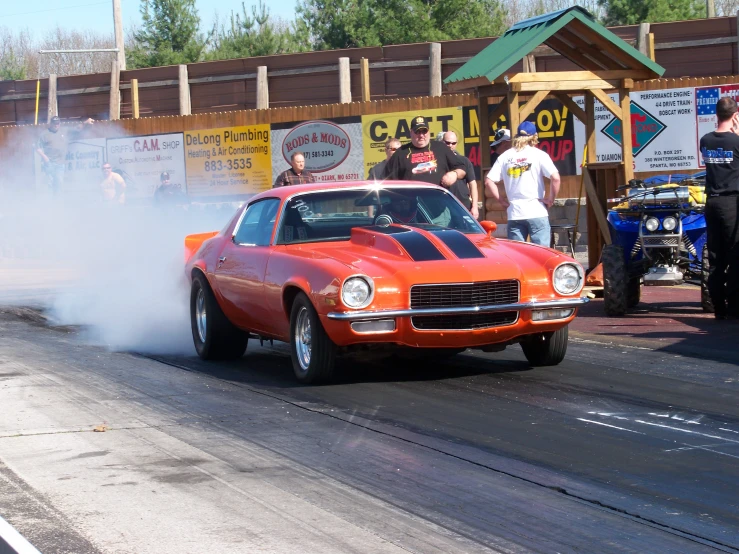 an orange car driving around a corner with a lot of dust