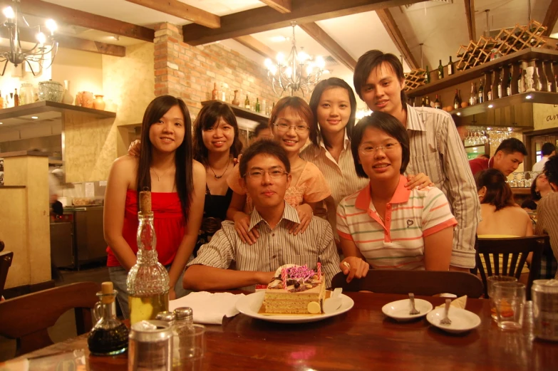 people are posing at a table with cake in front