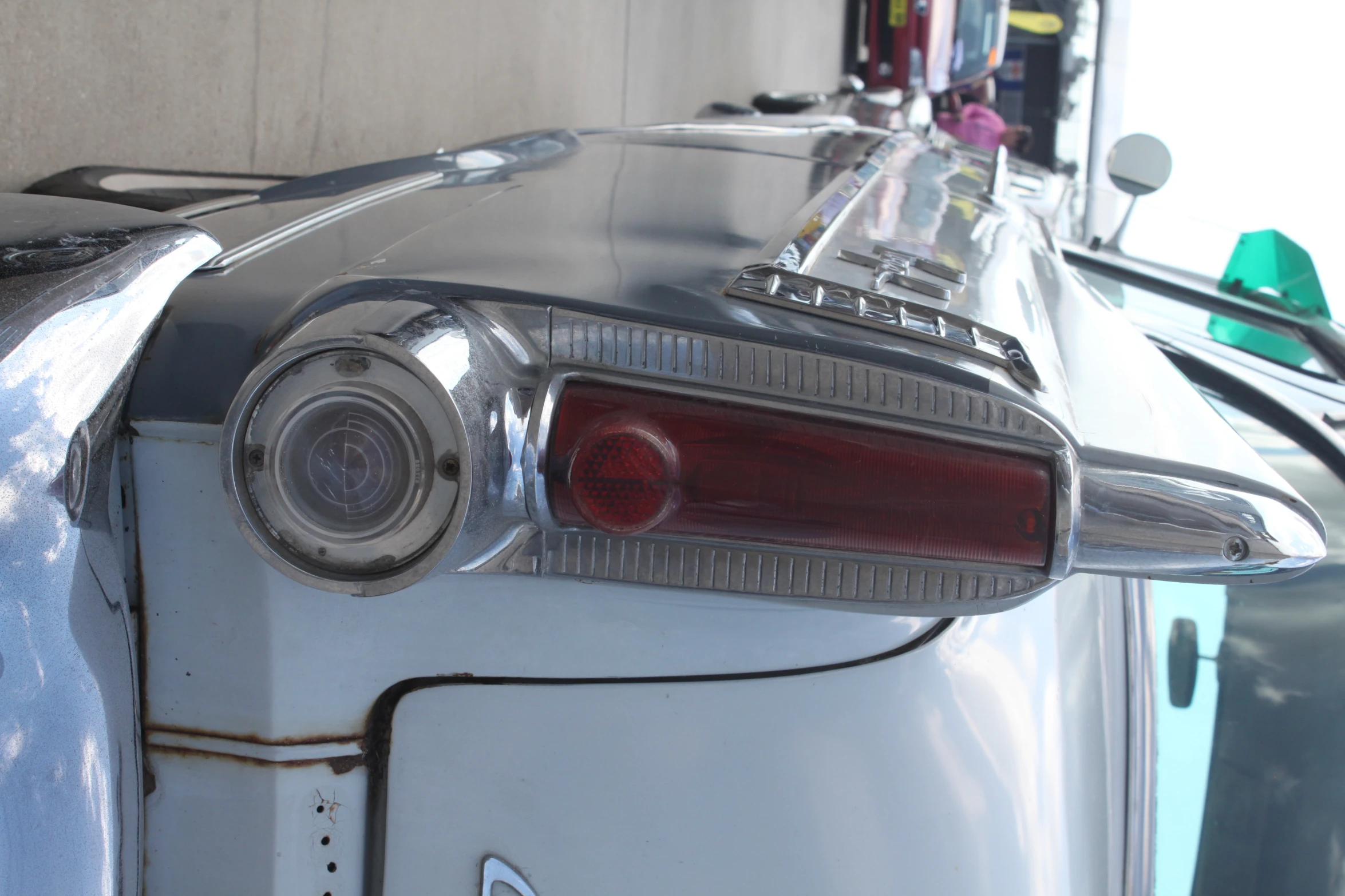 a silver car parked next to a sidewalk in front of other cars