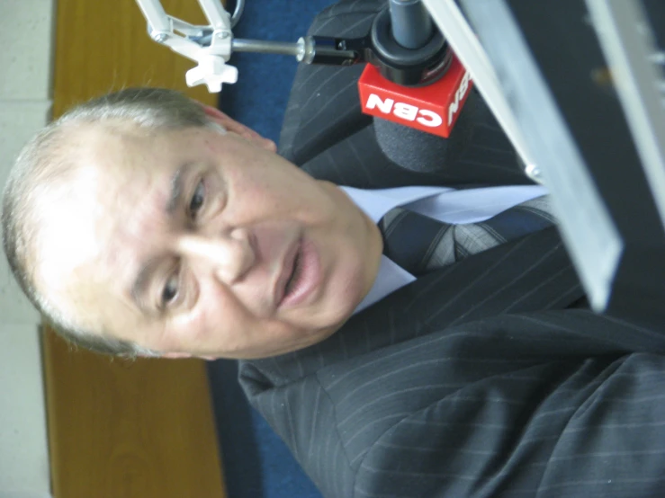an older businessman with a microphone behind him