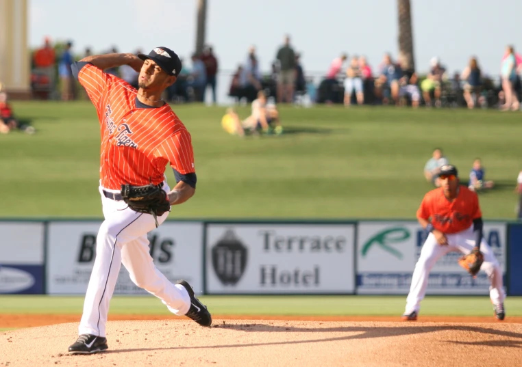 a pitcher winds up for a pitch in front of the crowd