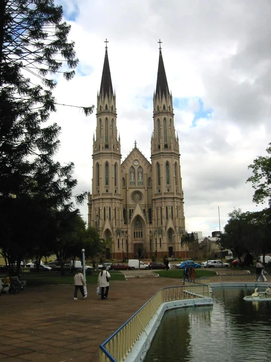 the cathedral has a clock tower above the water and is reflecting in the pond