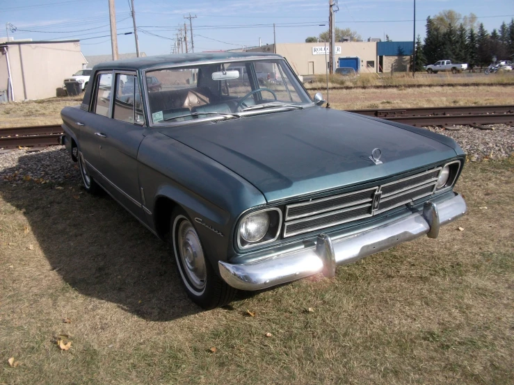 a small blue car sits parked in a field