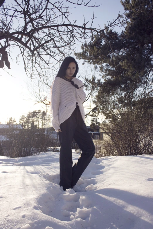 a woman posing in the snow near a tree