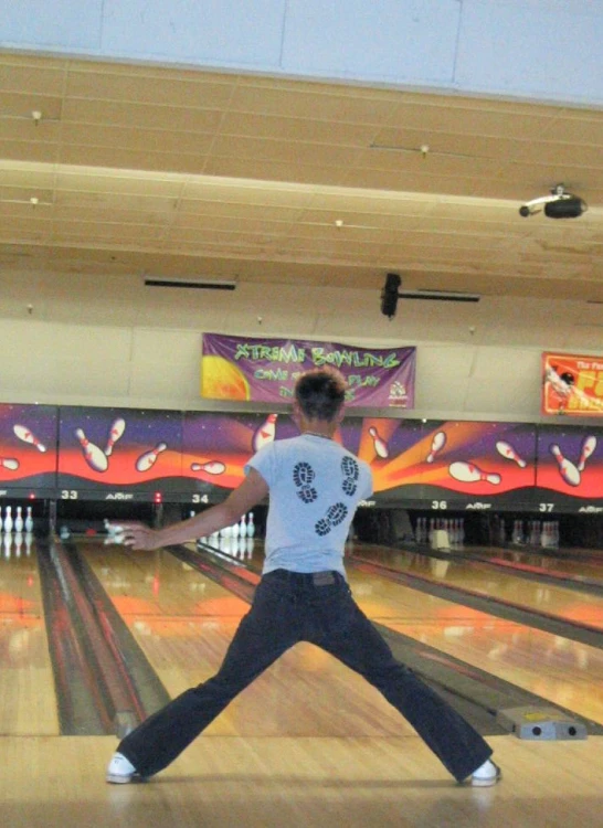 a man with his arms wide open standing on a bowling alley