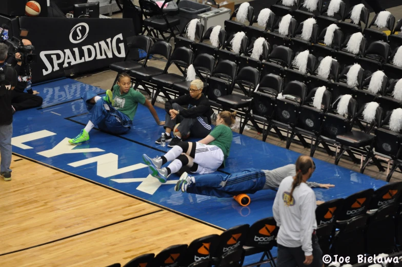 two ladies and a male in green are sitting on the blue floor