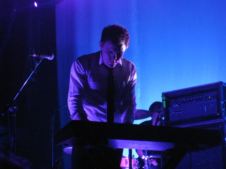 a man is standing next to his keyboard in a dark room