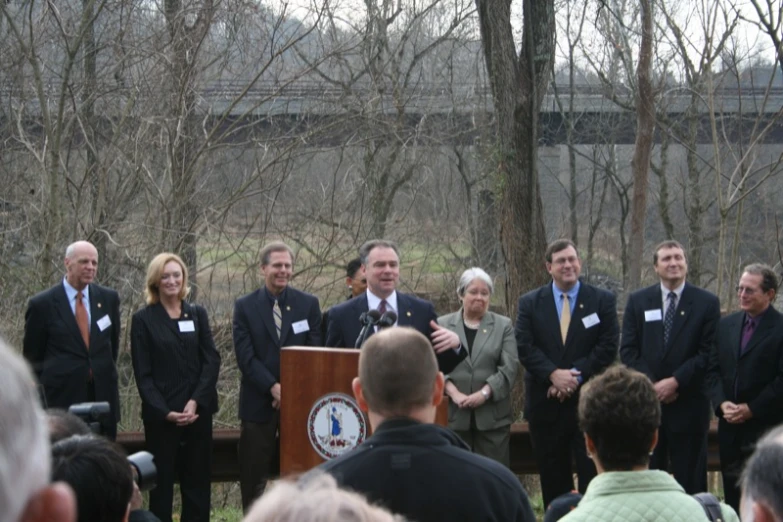 several people wearing suits and ties are gathered around a podium