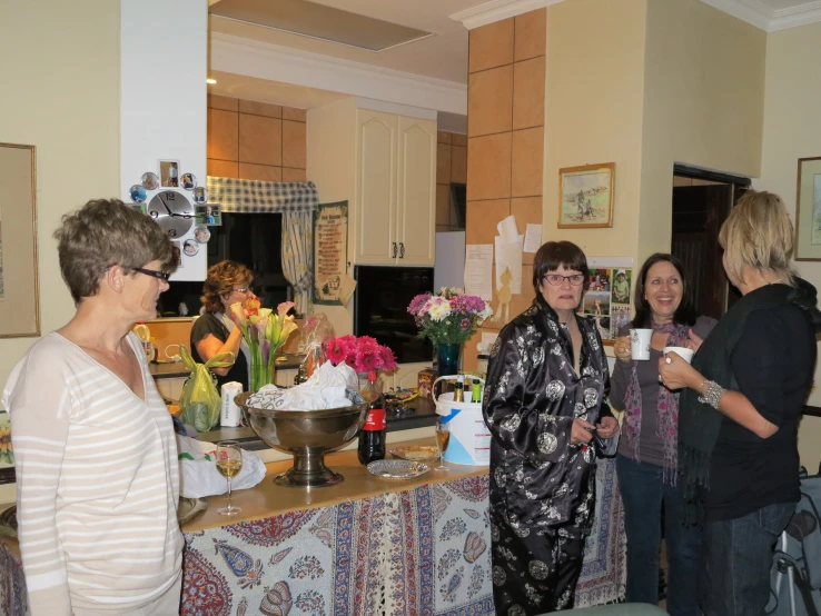 three women are standing in the kitchen talking to each other