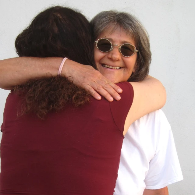 two women hug and look into the camera