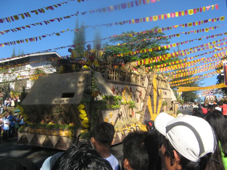 people watching a float decorated with garland and flags