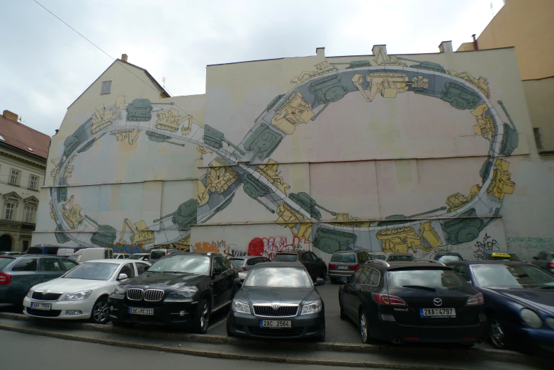 a mural on the side of a building with several cars parked in front