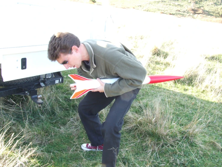 a man crouches down beside a white car