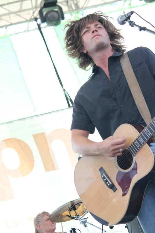 a man holding an acoustic guitar near a stage