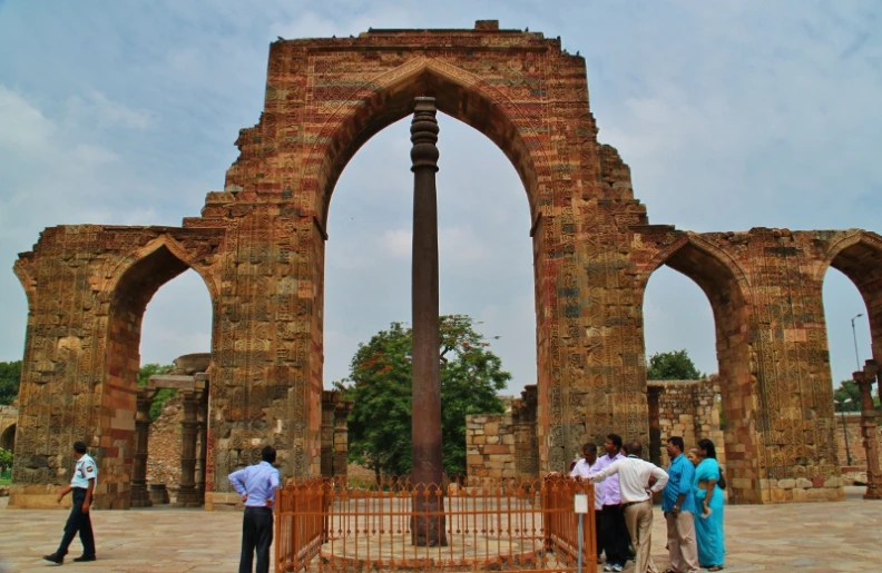 people stand in front of an old arch